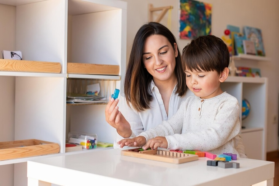 An occupational therapist at Interactive Minds in Bahrain guides a young boy through a colorful block-sorting activity to improve cognitive skills.