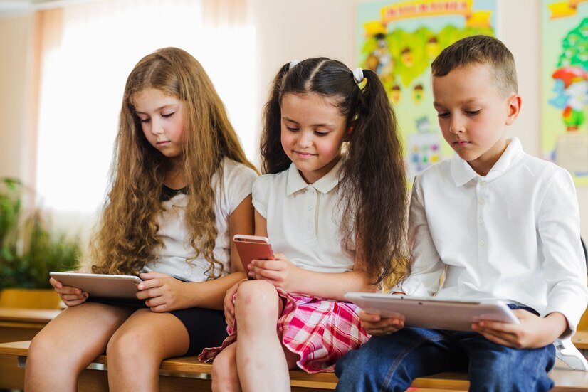 Three young students sit together using tablets and a phone, illustrating a blog topic on screen time by Interactive Minds in Bahrain.