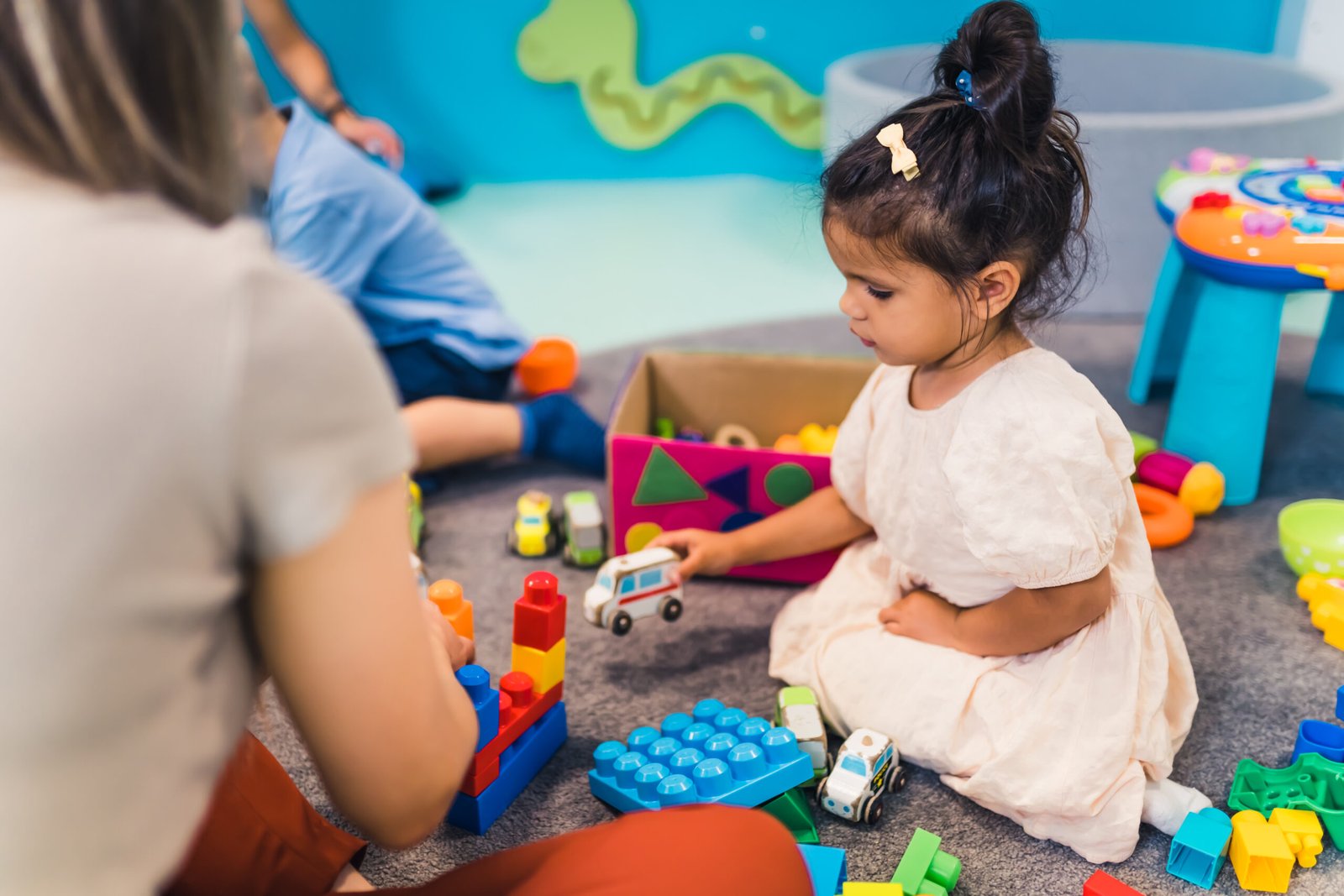 A young girl in an Early Intervention session at Interactive Minds in Bahrain, learning through play with a toy ambulance to develop motor skills.