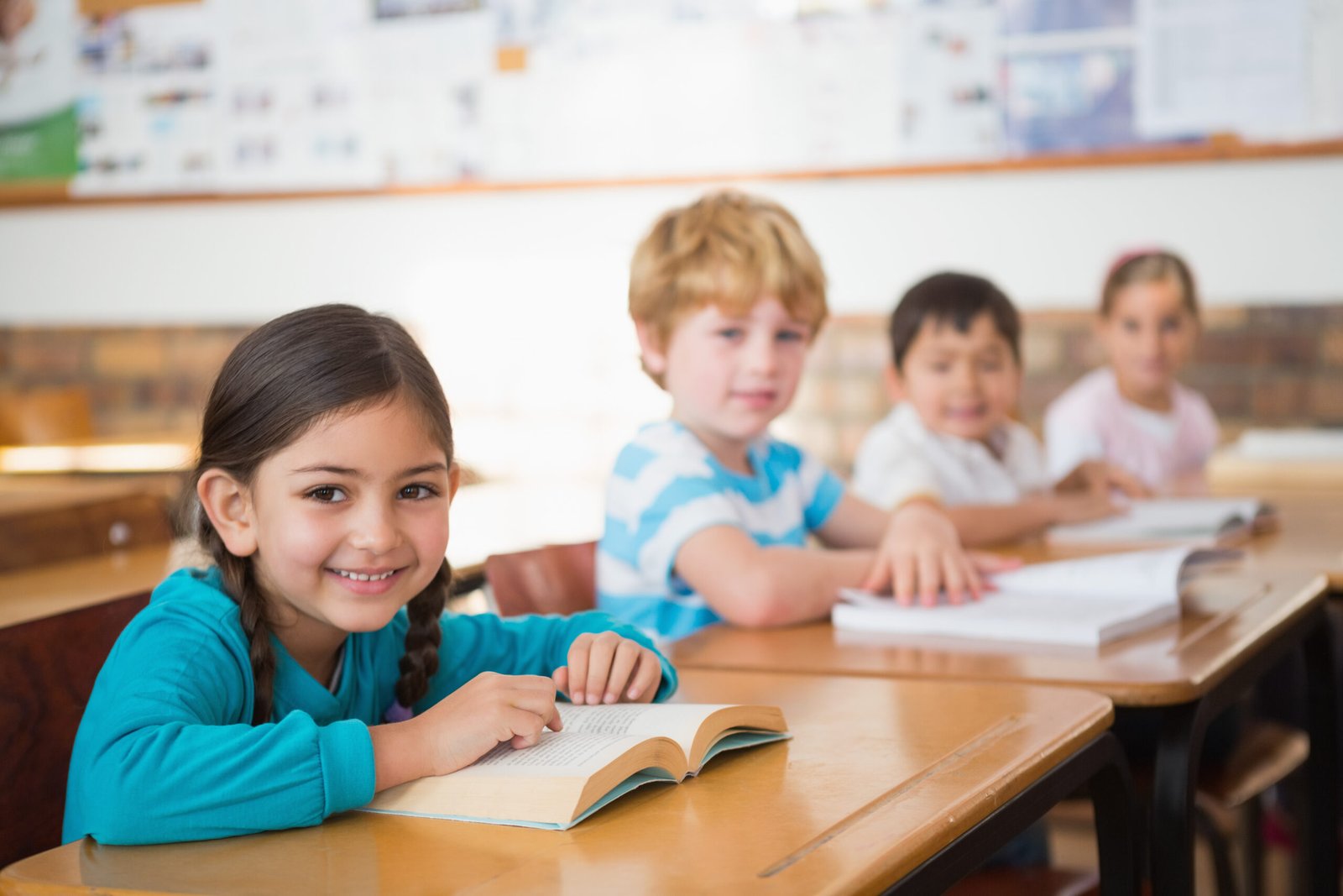 A young female student smiles at her desk in a Bahrain classroom, feeling confident with her reading skills