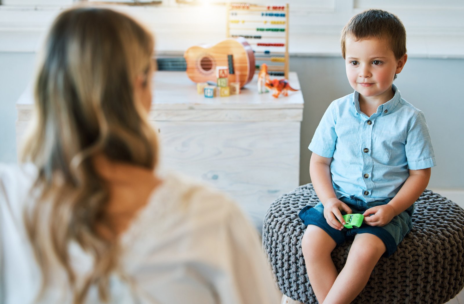 A young boy sits calmly during a one-on-one therapy consultation at Interactive Minds in Bahrain, focusing on the therapist.