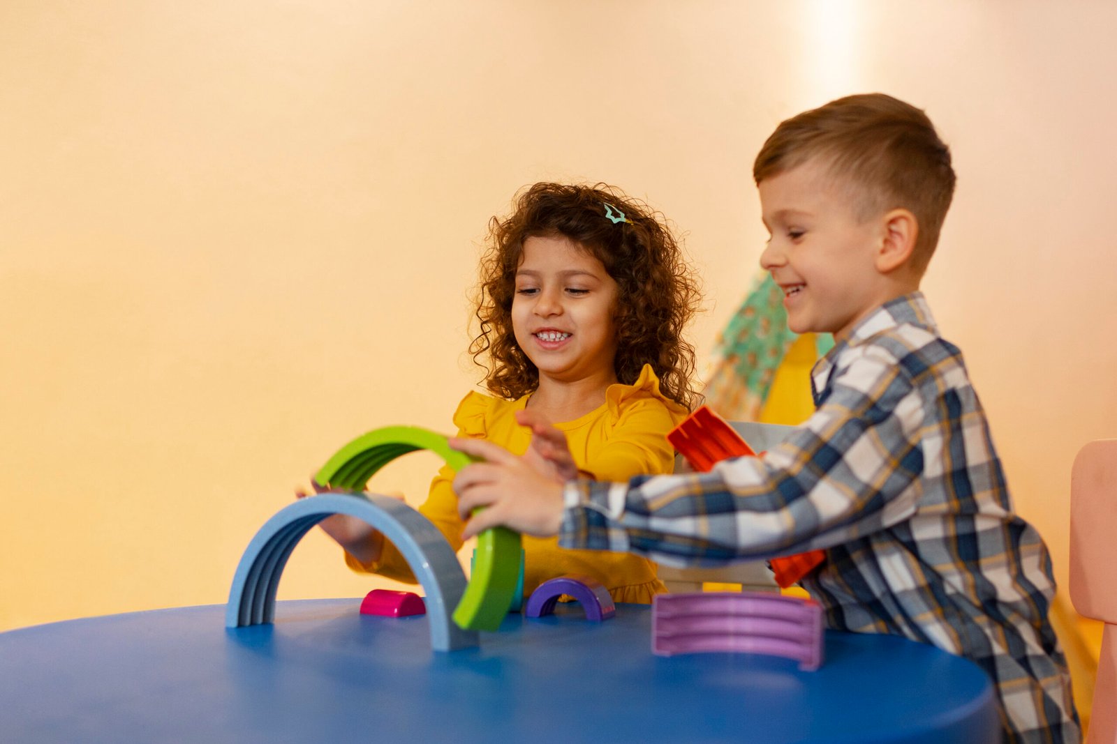 A young boy and girl work together in a social skills group at Interactive Minds in Bahrain, building a rainbow with eco-friendly toys.
