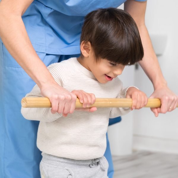 Physiotherapist and kid walking in rehabilitation center. Doctor supports a children with cerebral palsy during physiotherapy treatment. High quality photo.